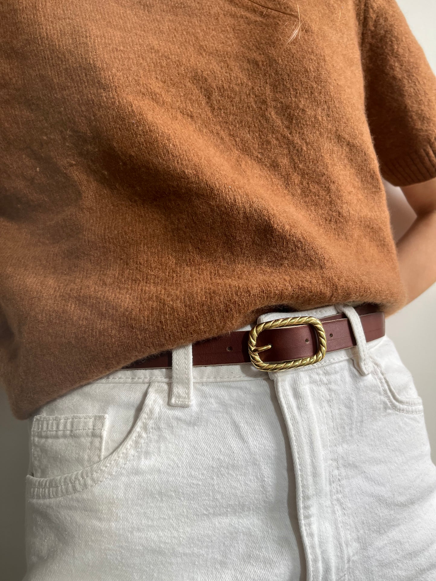 ceinture chic avec une boucle en laiton plein et un cuir couleur châtaigne tanné végétalement, portée sur un jean blanc