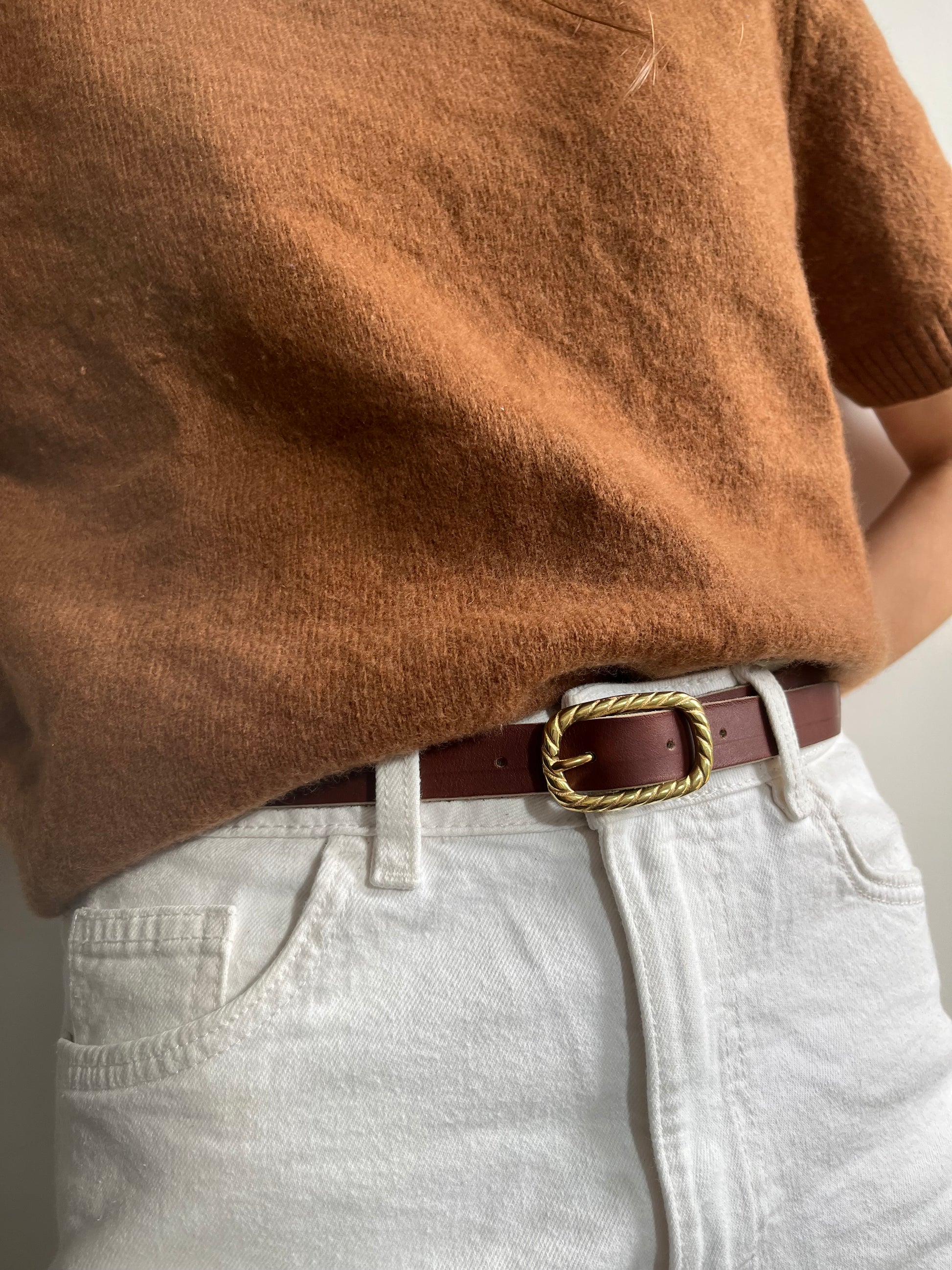 ceinture chic avec une boucle en laiton plein et un cuir couleur châtaigne tanné végétalement, portée sur un jean blanc